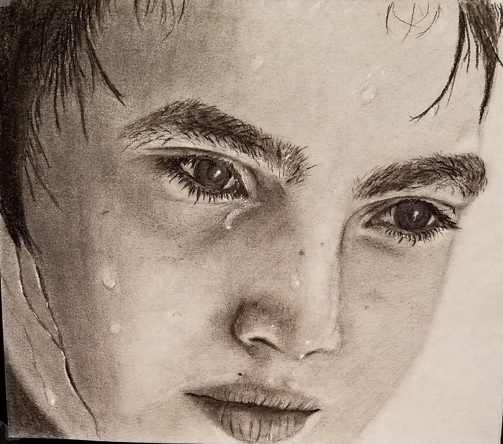 Pencil drawing of a nine-year-old boy’s face. The boy has wet hair and water droplets trickling down his face like he just came in from the ocean or is perhaps sweating