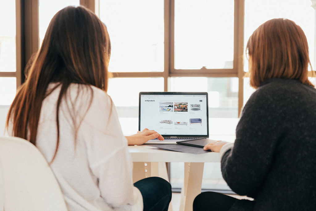 A woman is showing something on a website to another woman