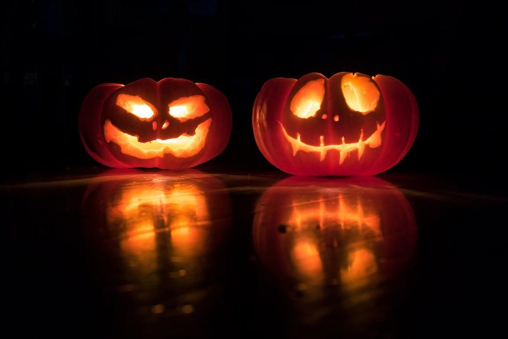 Two jack-o-lanterns glowing against a dark background.