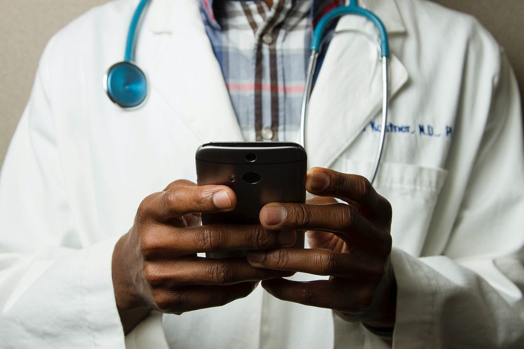 Male doctor typing on a mobile phone