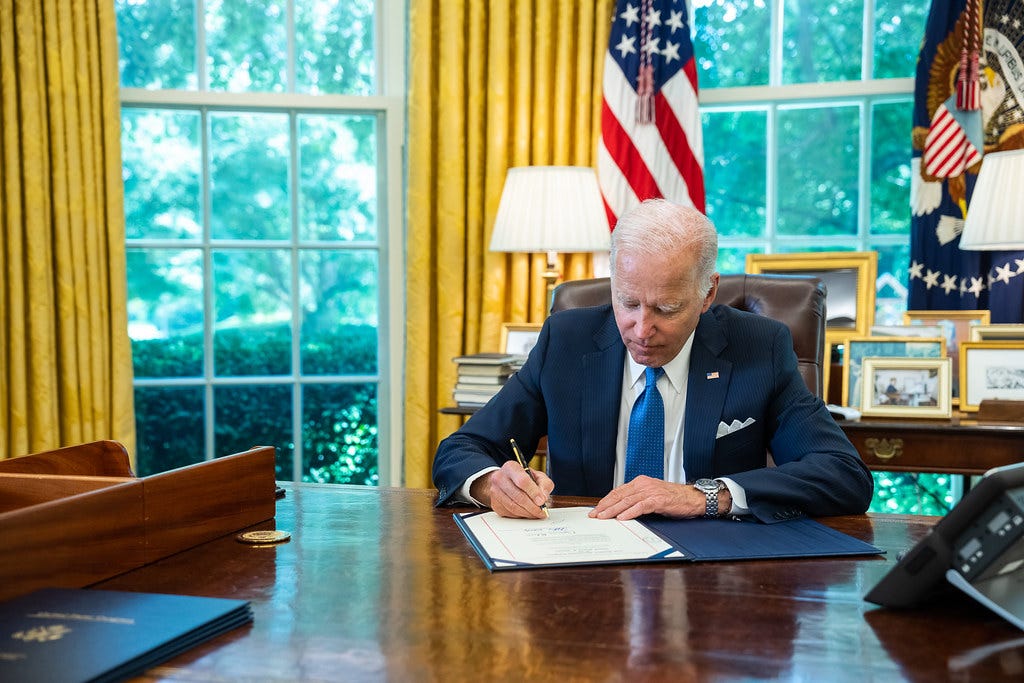 President Biden signing documents in Oval Office