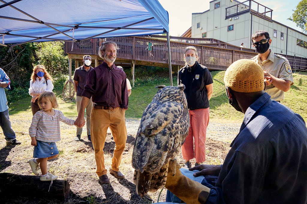 a person holds an owl while facing a small crowd of people