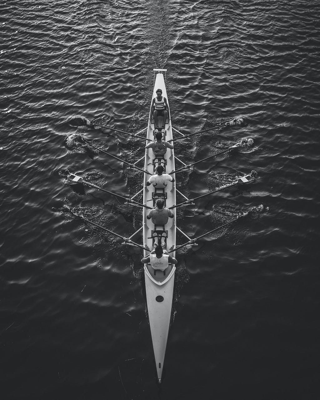 Foto vista de cima com pessoas remando uma canoa de competição.