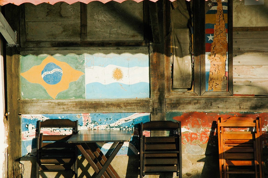 Three chairs propped against a wall. Brazil and Argentina flags are painted on the wall.
