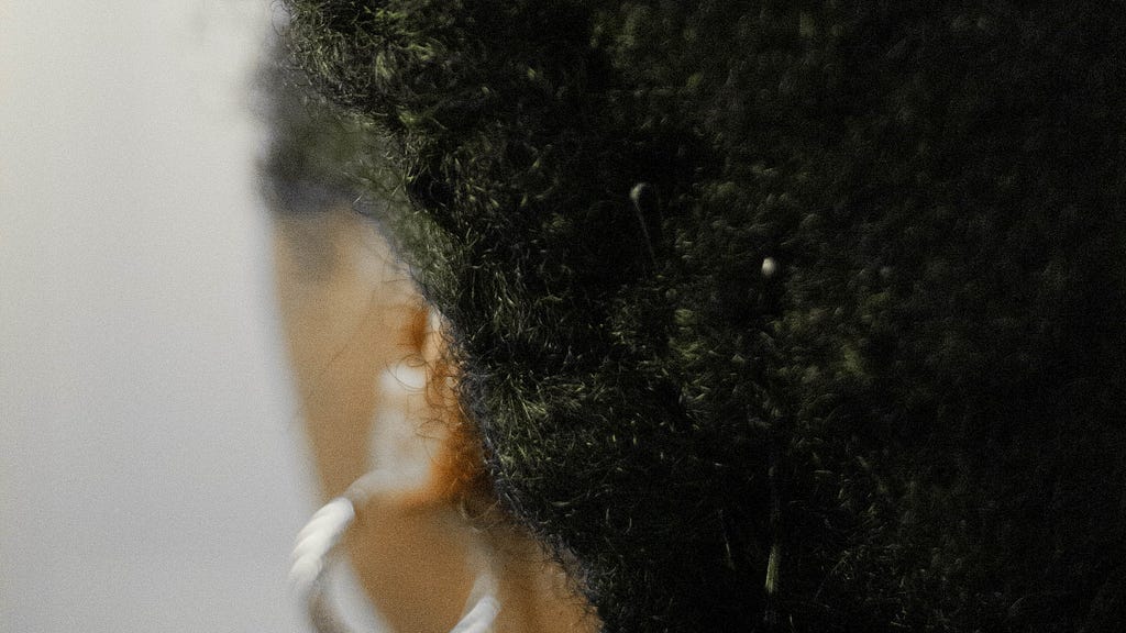 A Black woman with an afro and silver-hoop earrings