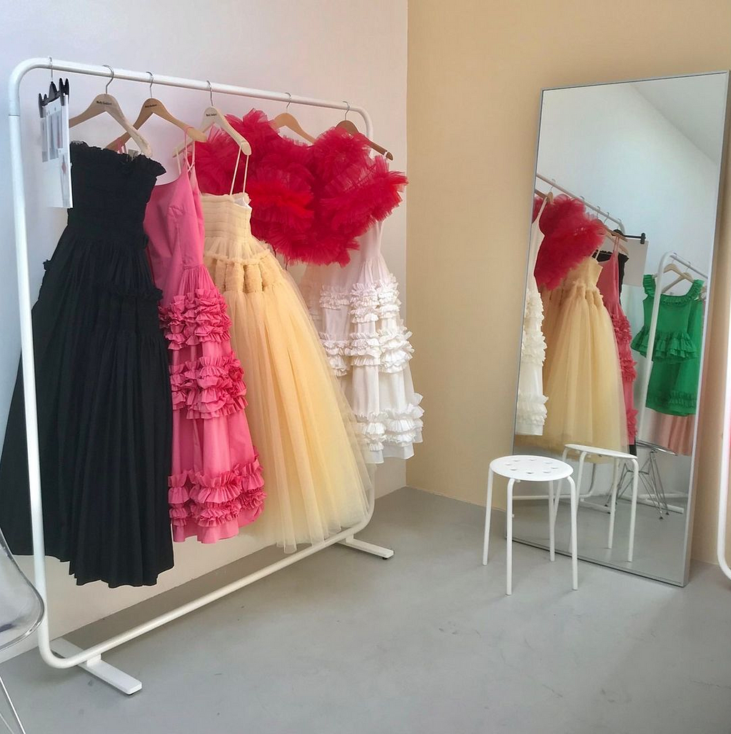 A rail of frothy tulle dresses with full skirts and ruffled trims by designer Molly Goddard. The colours are black, pink, yellow, red and white.
