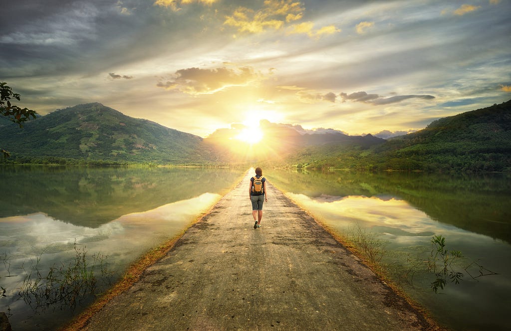 Beautiful vista showing a traveler walking along a path with mountains in the distance.