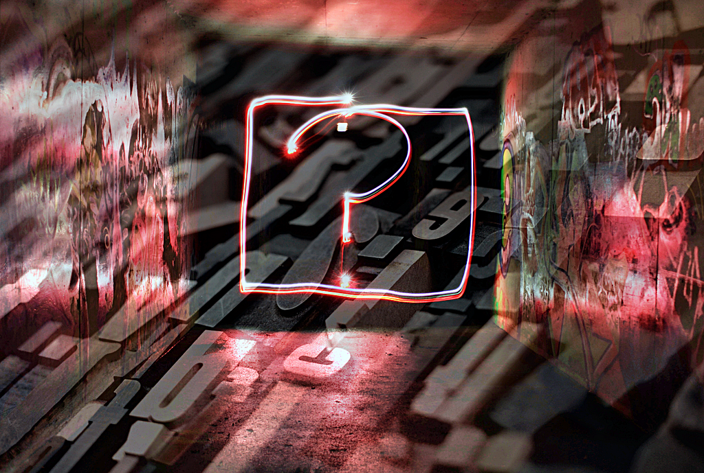 Blocks of letters and numbers overlaid with a neon question mark and graffitied walls