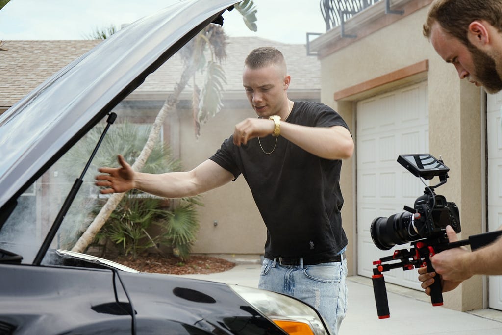 man actor and camera man framing film shoot car for videos directing