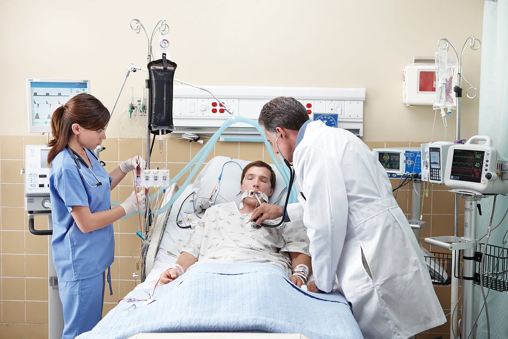 A patient and clinicians in an intensive care unit.