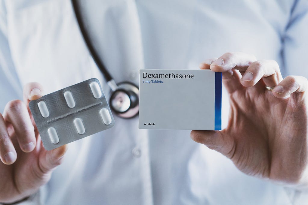 A person in a white lab coat holds a box of dexamathasone, the drug estimated to have saved a million lives worldwide from Covid-19