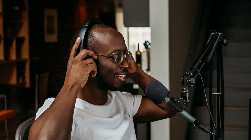 Black man with headphones in a studio recording a podcast
