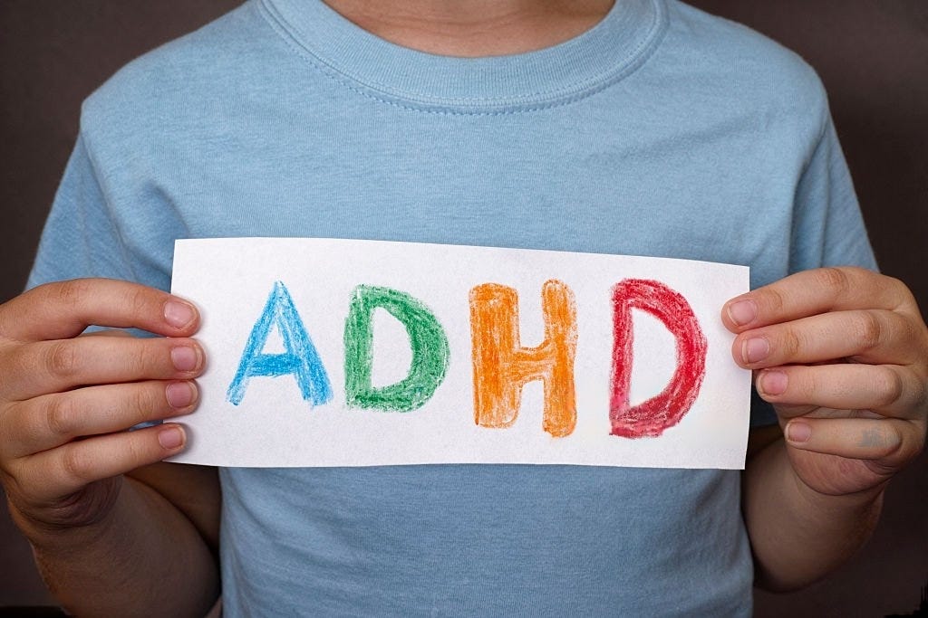 Image: A man holding a paper with the text ADHD written on it