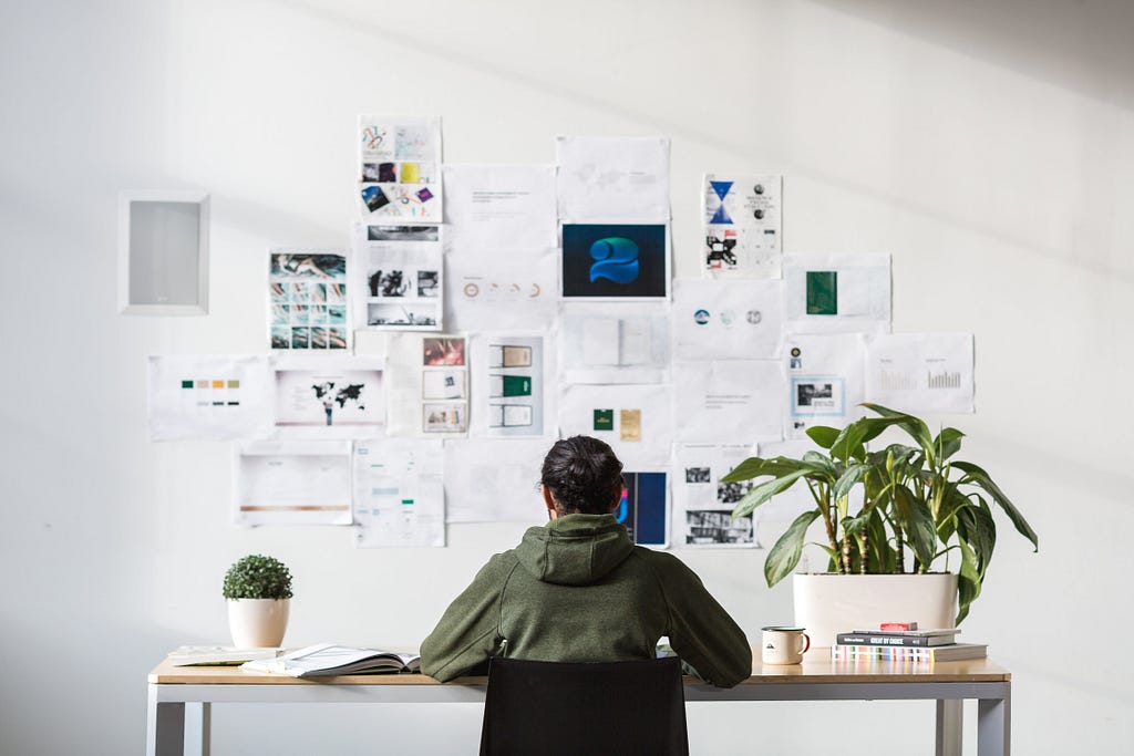 A creative person operates from a home office where a wall adorned with images from a brainstorming session serves as a wellspring of inspiration.