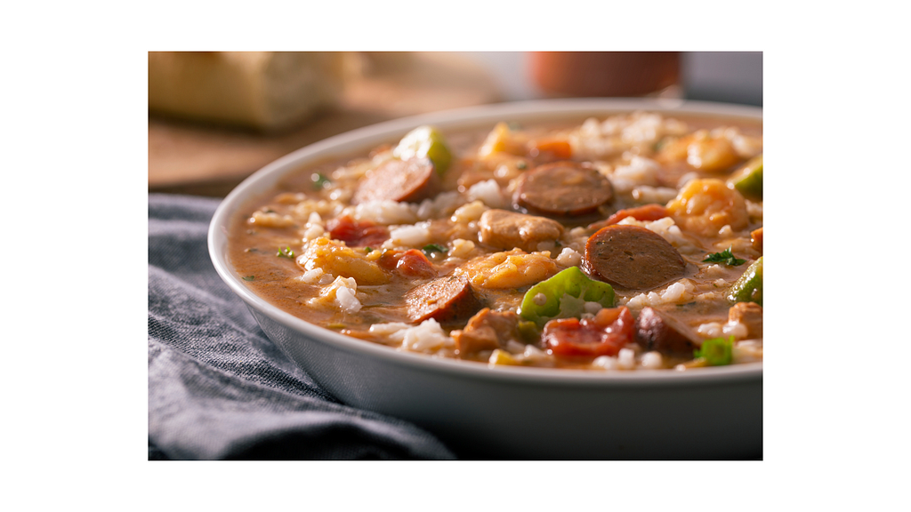 A bowl of authentic Creole gumbo, rich and hearty, filled with slices of sausage, shrimp, okra, and rice, served in a deep bowl, symbolizing the warmth and complexity of this traditional dish.