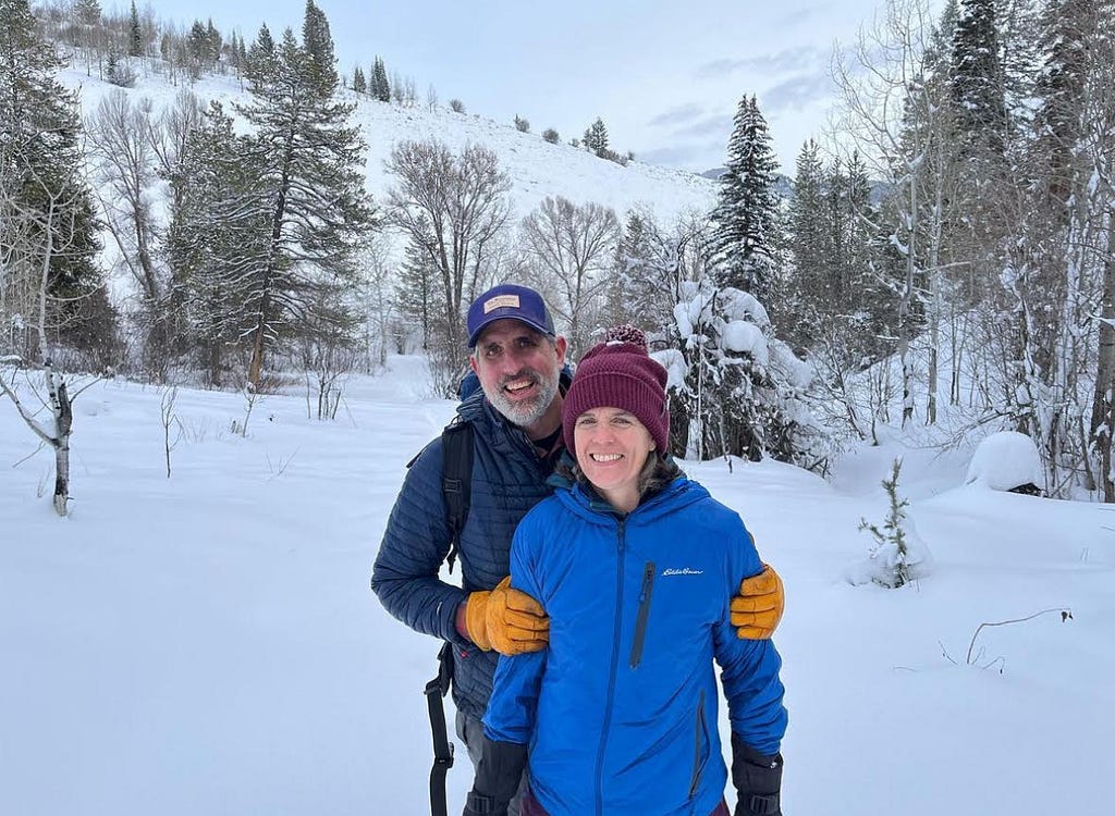 Man standing behind woman in the outdoors on a snowy day