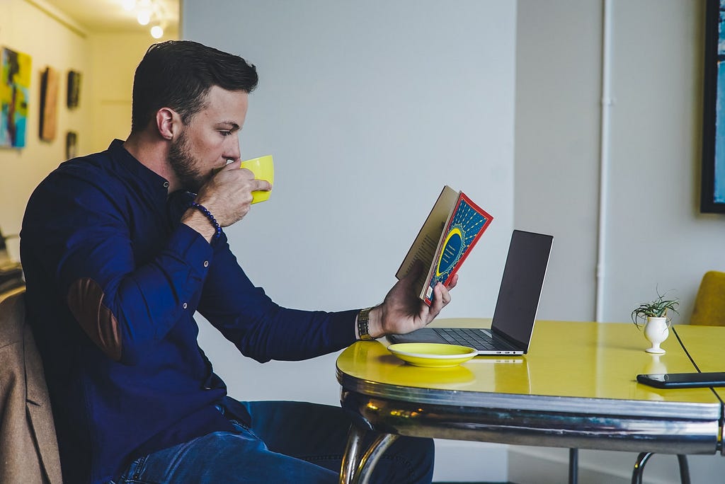 man reading book at table