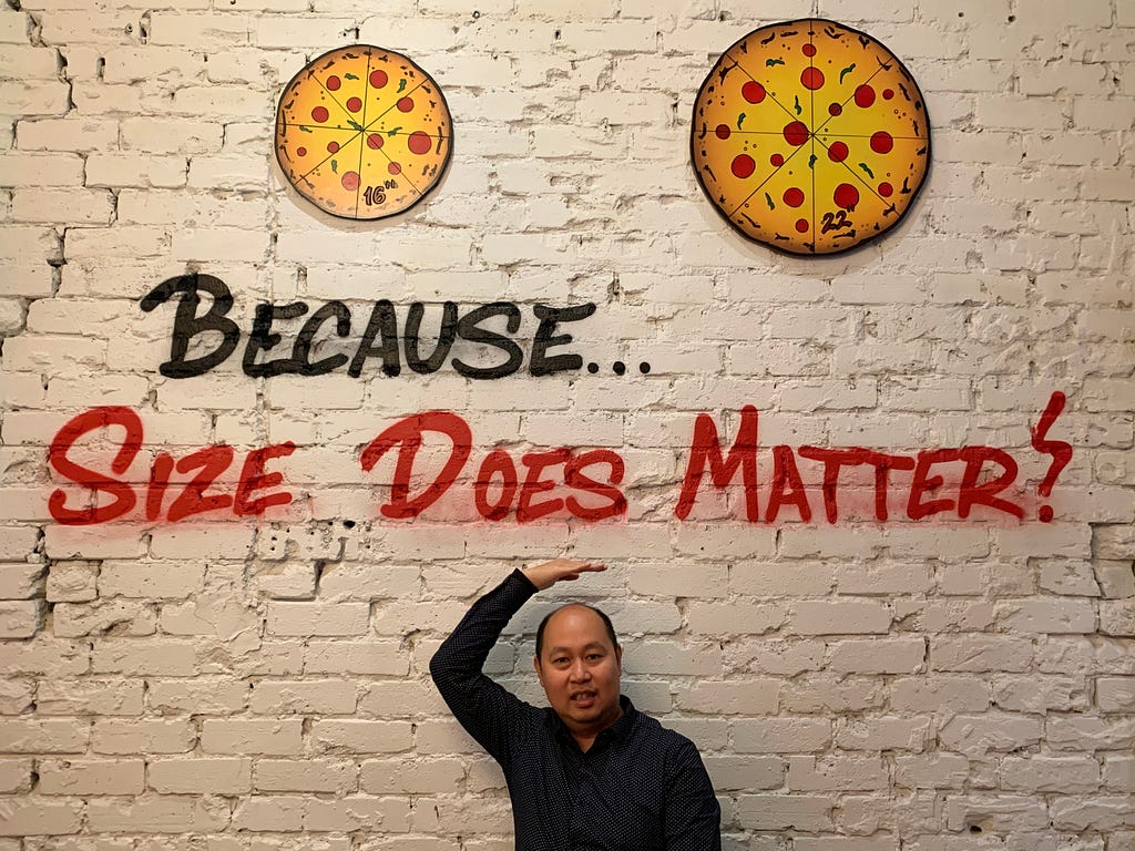 The author in front of the sentence — written on a wall — “Because… Size Does Matter!”