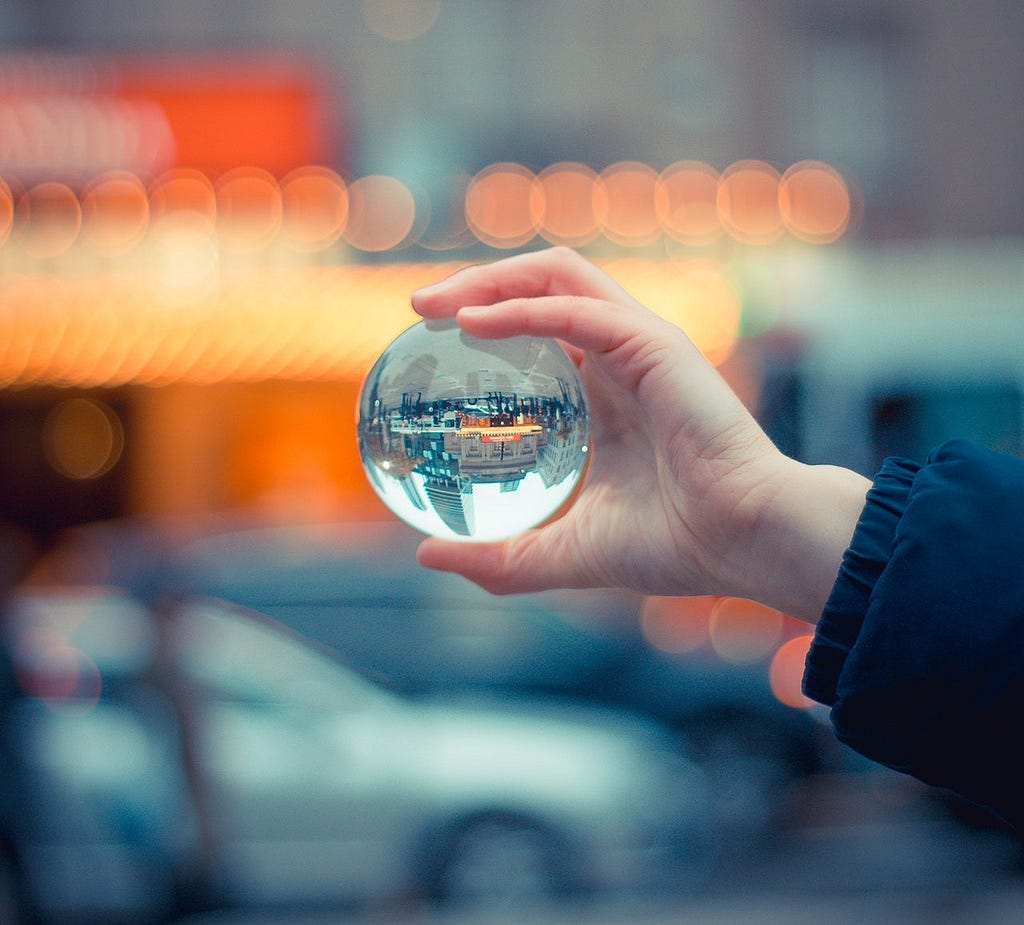Person holding a glass ball which reflects a cityscape