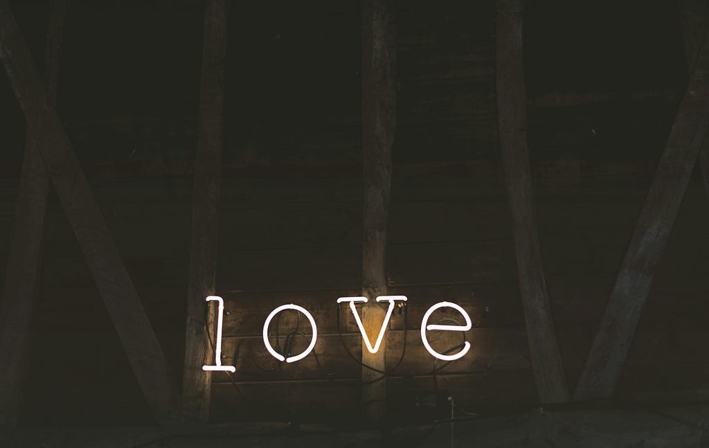 Lettering in separate neon lights spell the word love [Credit: Jez Timms on Unsplash].