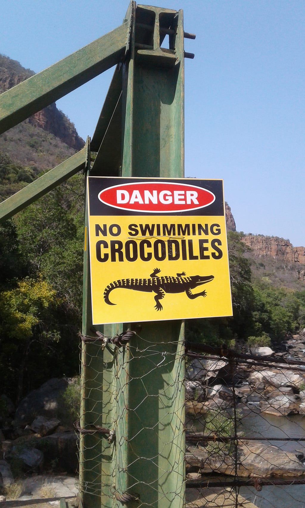 A crocodile danger sign warning hikers not to swim in the river