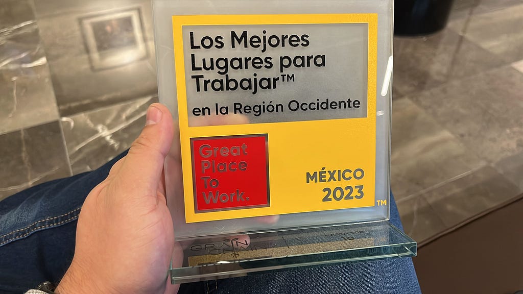 An unseen GrainChain team member holds our glass award, which says “Los Mejores Lugares para Trabajar en la Region Occidente,” Great Place to Work, and Mexico 2023.