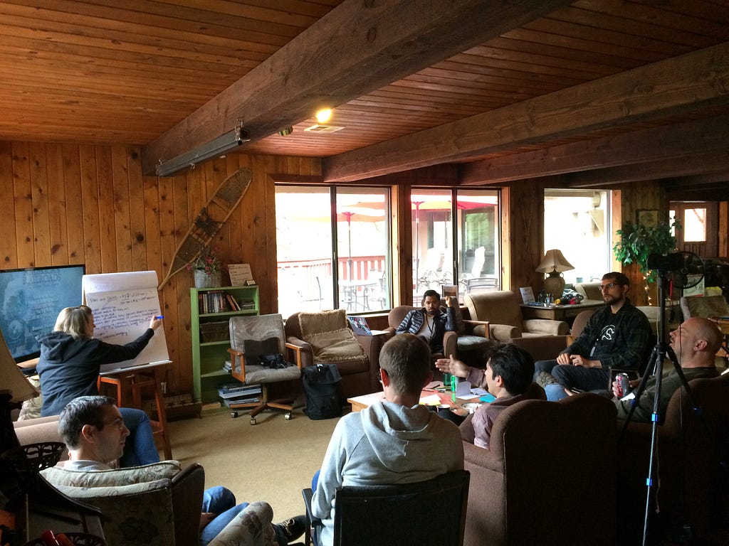 Offline Camp participants having a discussion in the living room of the Protocol Labs lodge while one of them takes notes.
