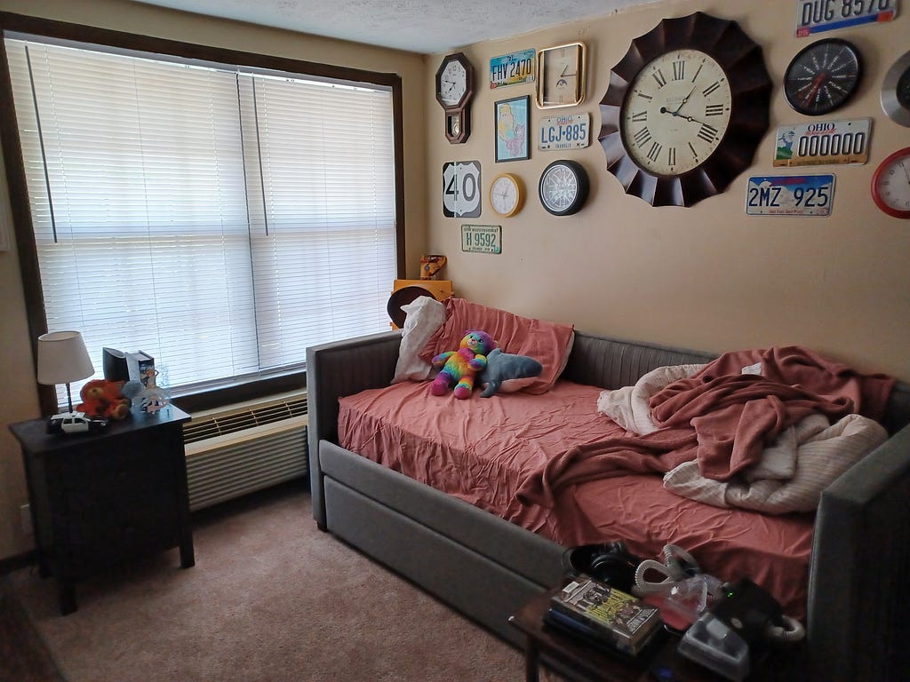 my bed, with several clocks mounted on the wall above it, including one very large one in the center