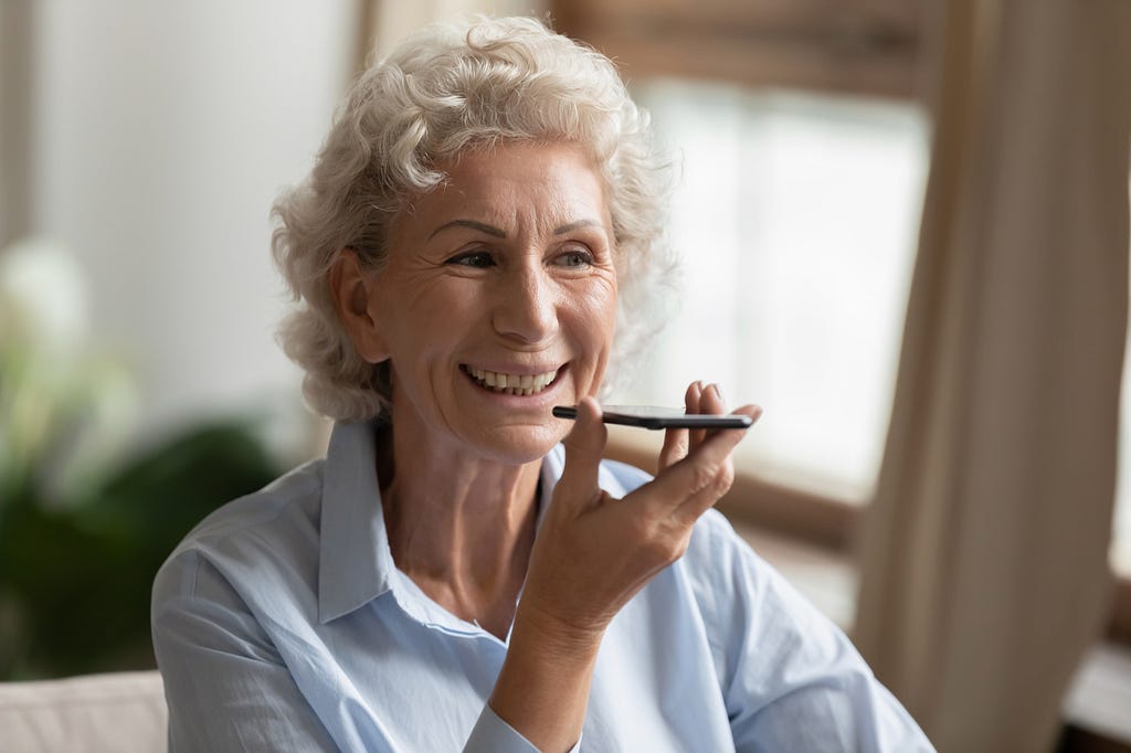 Old woman using a voice assistant on her phone.