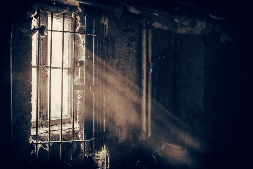 Sun shines through cellar window with metal bars