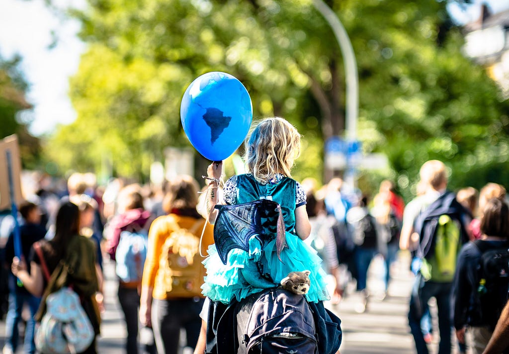 Little girl holding a blue balloon representing the Earth at climate protest