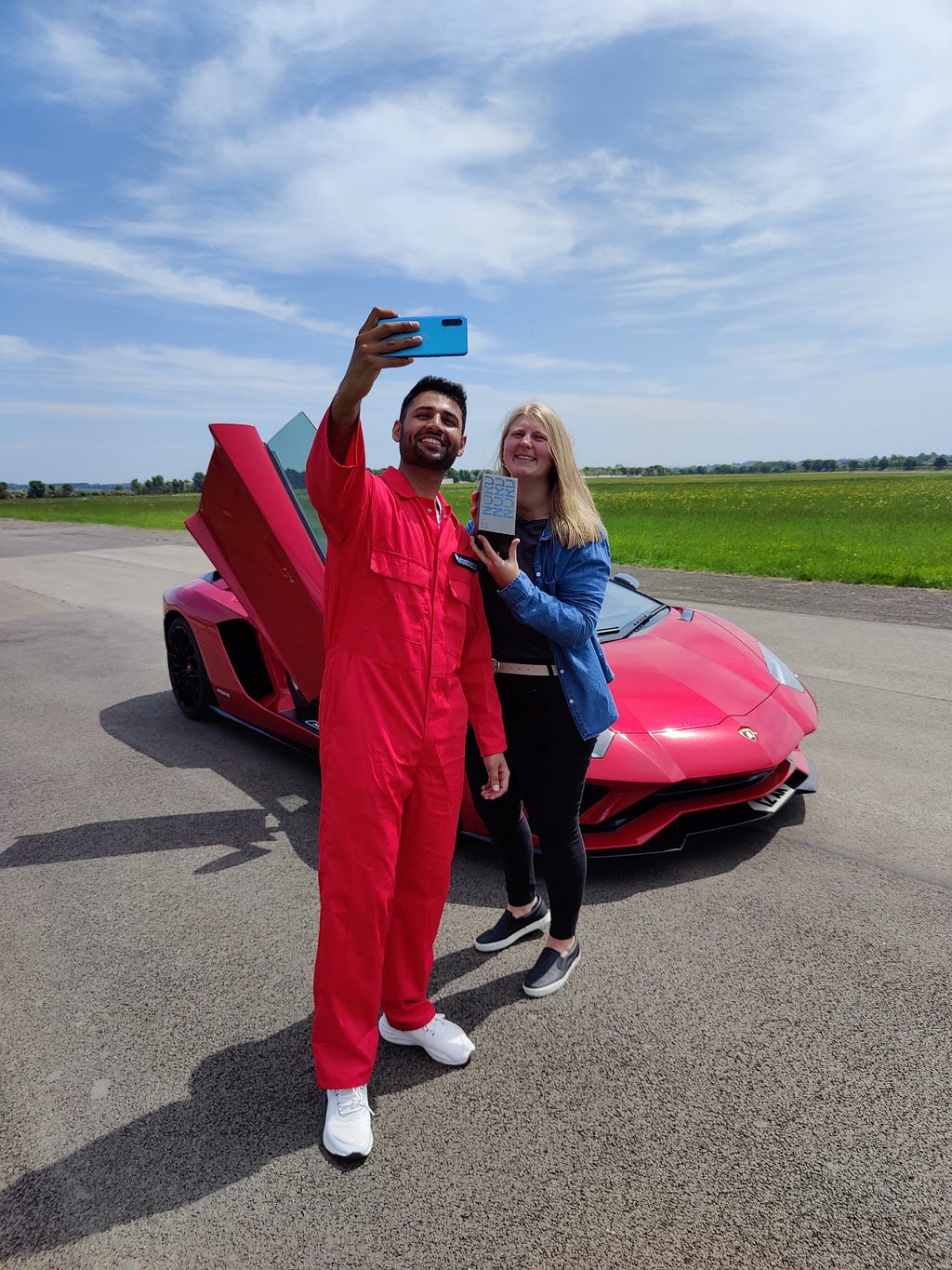 Mrwhosetheboss taking a selfie on the OnePlus Nord CE with Sophie who is holding the box on an airfield with a Lamborghini behind.