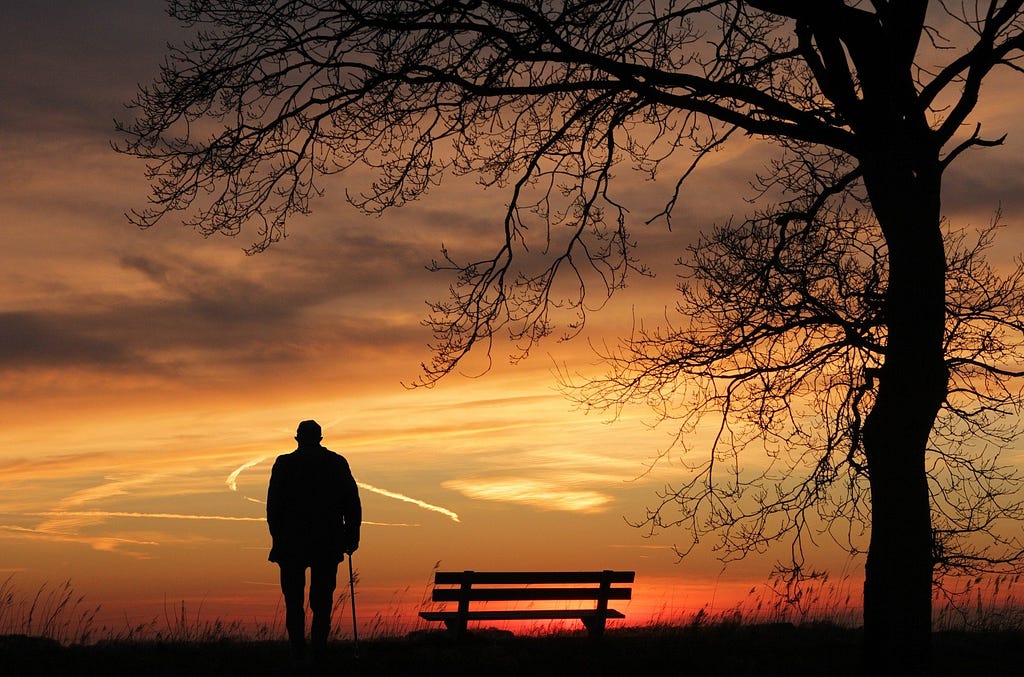 man watching the sunset near a bench
