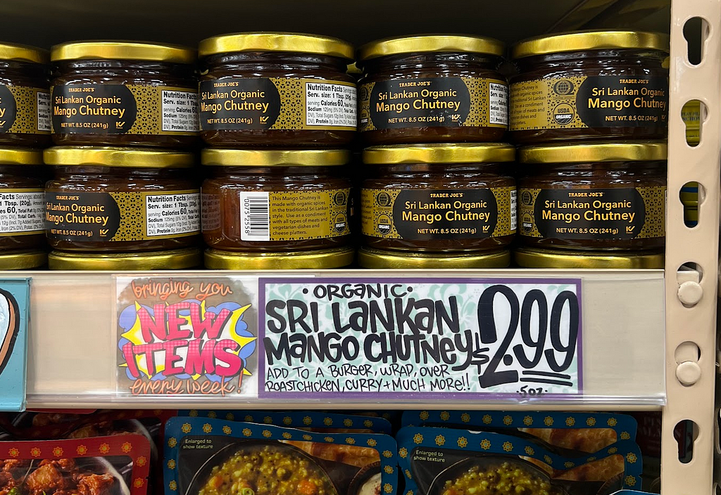 Product tag that says “Bringing you New Items every week! Organic Sri Lankan Mango Chutney (Add to a burger, wrap, over roast chicken, curry + much more!!)”