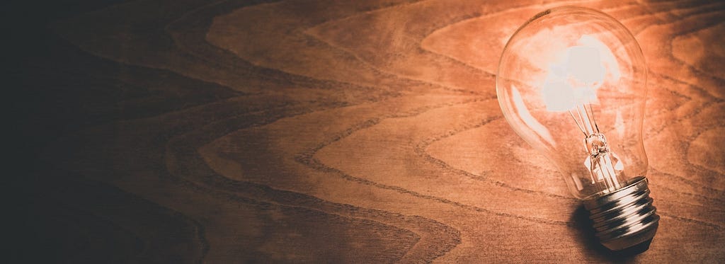 A lightbulb illuminates a wooden desk