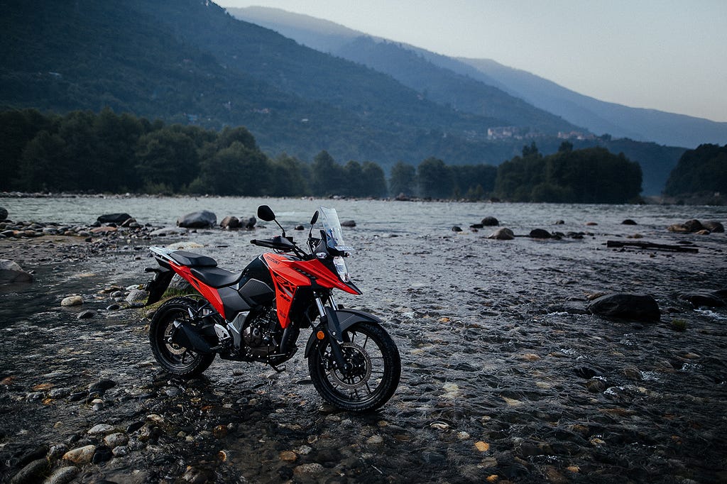 Suzuki V Strom motorcycle parked at the hilly area near a river.