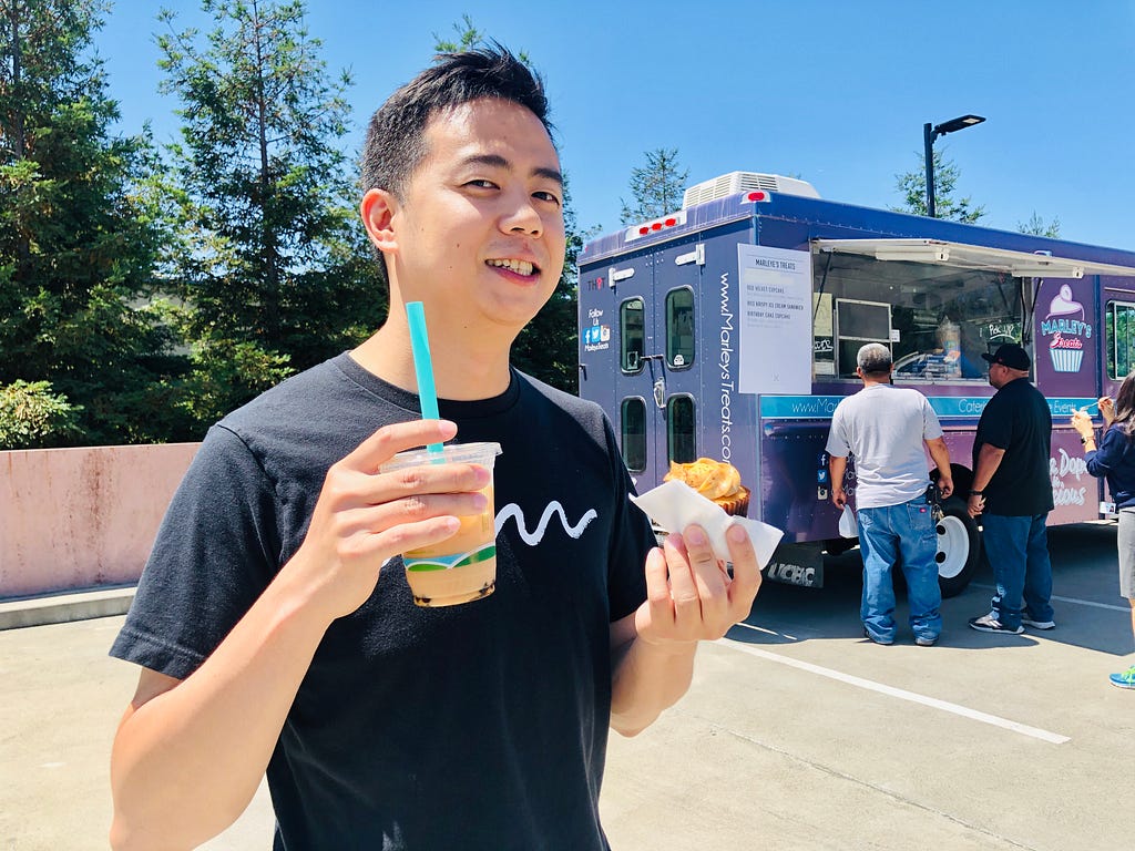 Chit Meng smiling while holding boba and a cupcake