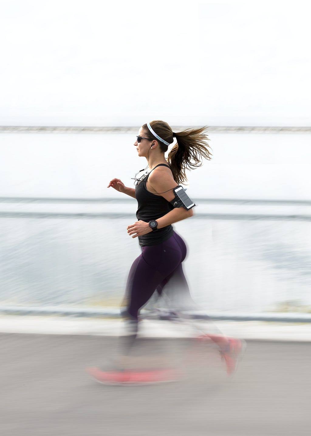 Woman running with phone strapped to her arm.