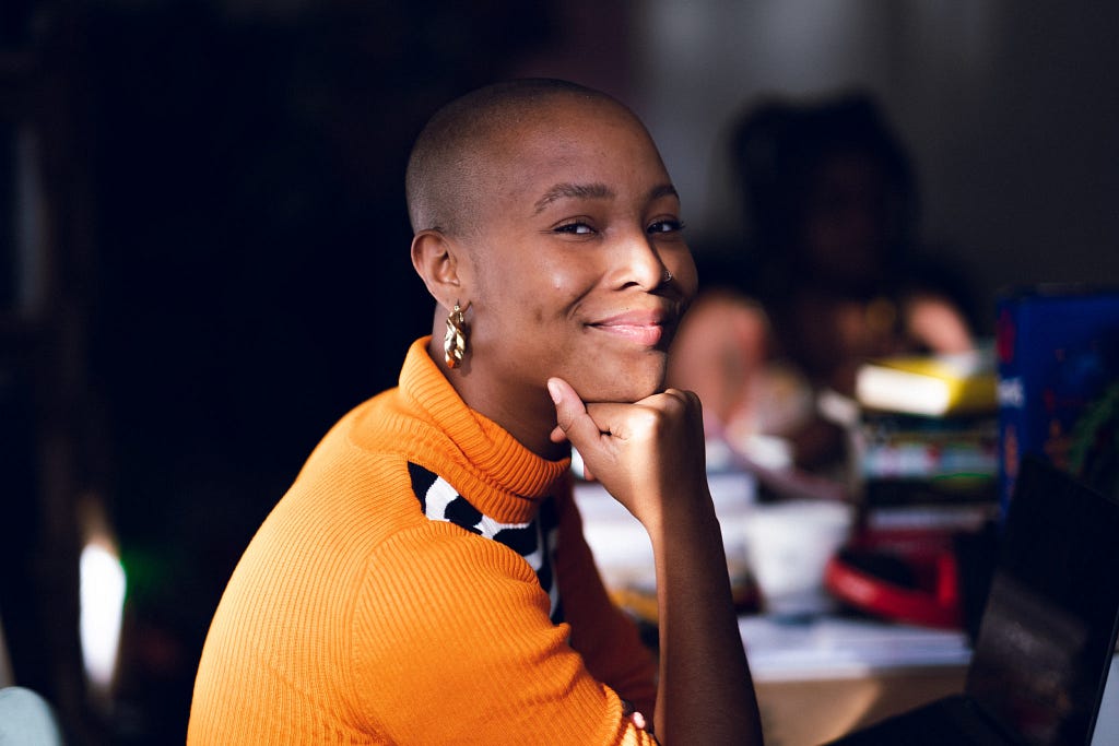 Liv Little, founder of gal-dem, resting her chin on her fist and smiling.