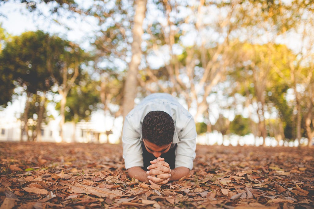 Man kneeling on ground praying