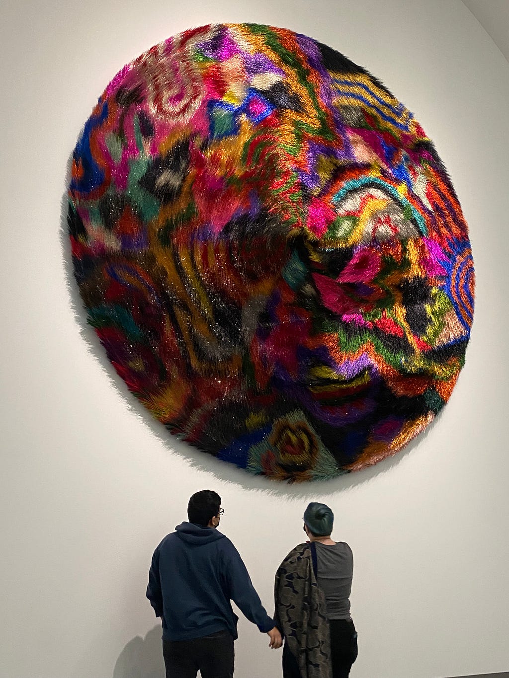 Image of two people standing in front of Nick Cave wall hanging