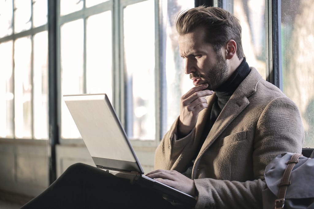 A picture of a man looking confused at a laptop