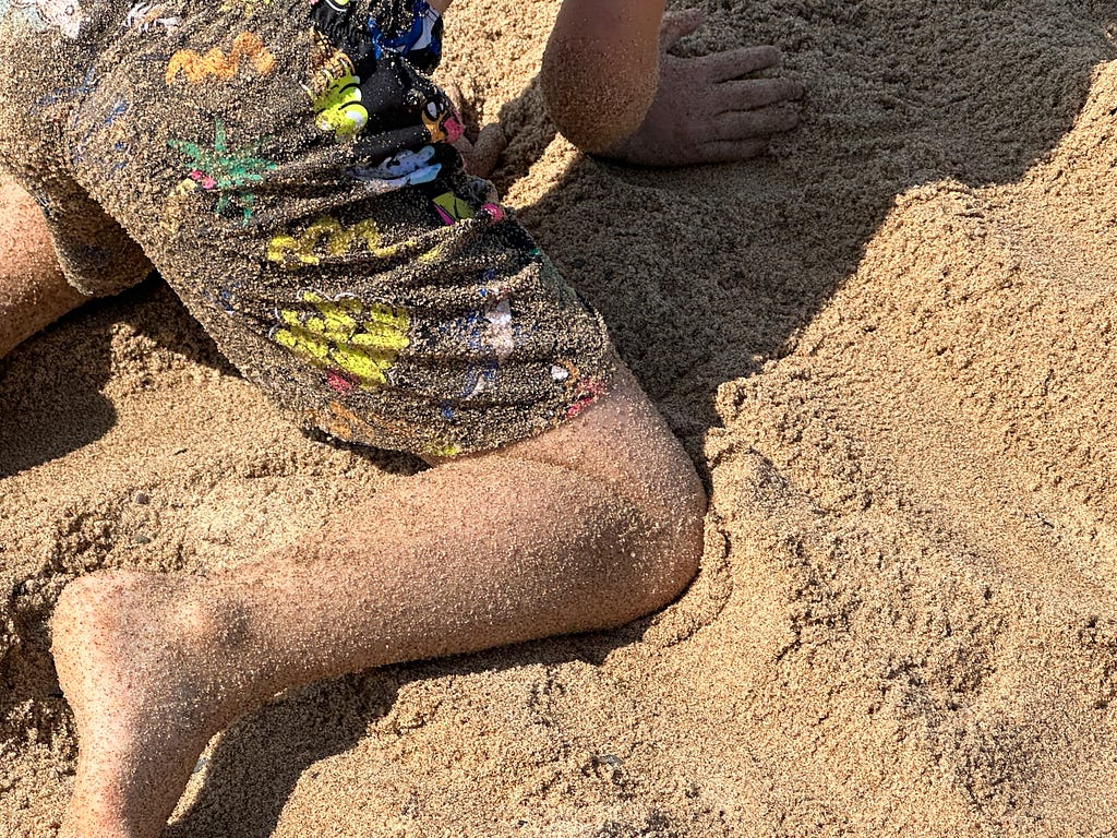 boy playing in beach sand