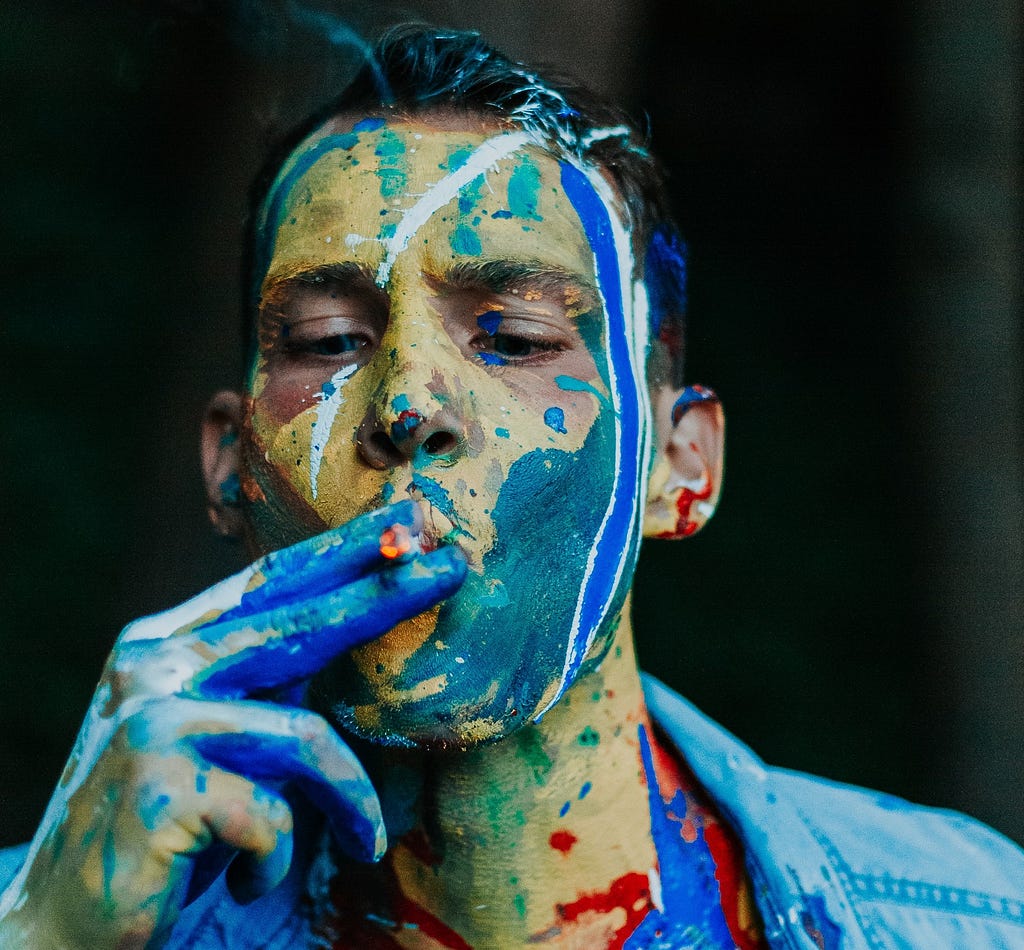 Photograph of splatter paint covered man smoking a cigarette