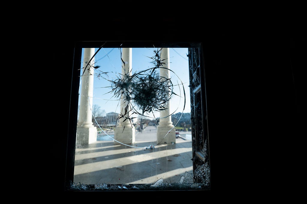 The east front of the U.S. Capitol seen through a shattered door in Washington, D.C., January 7, 2021. Photo by Bill Clark/CQ Roll Call via AP Images