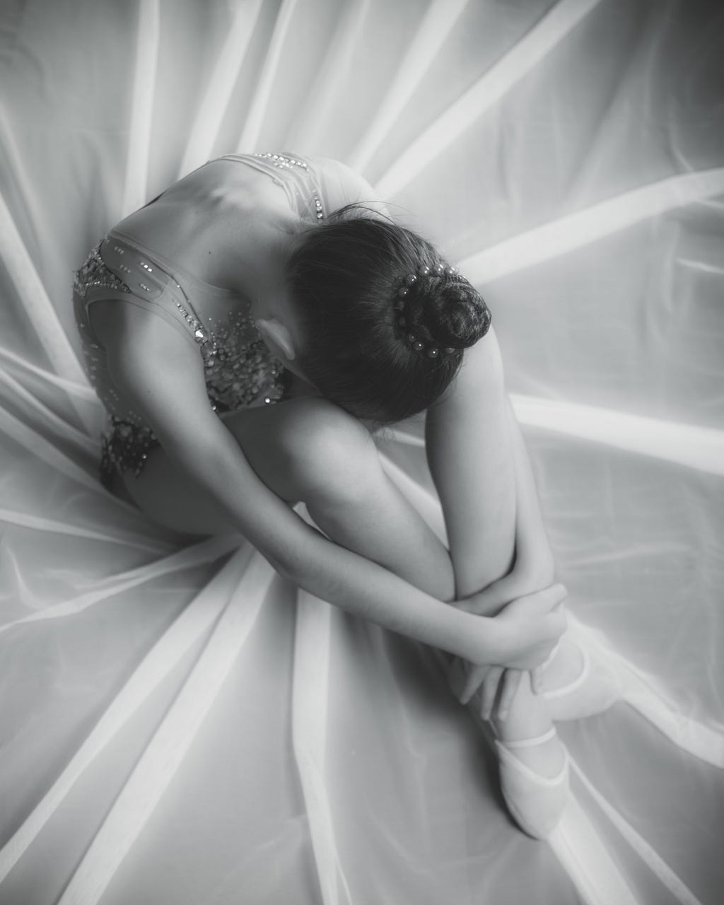 Black and white photo of a sad ballerina, curled up in a ball