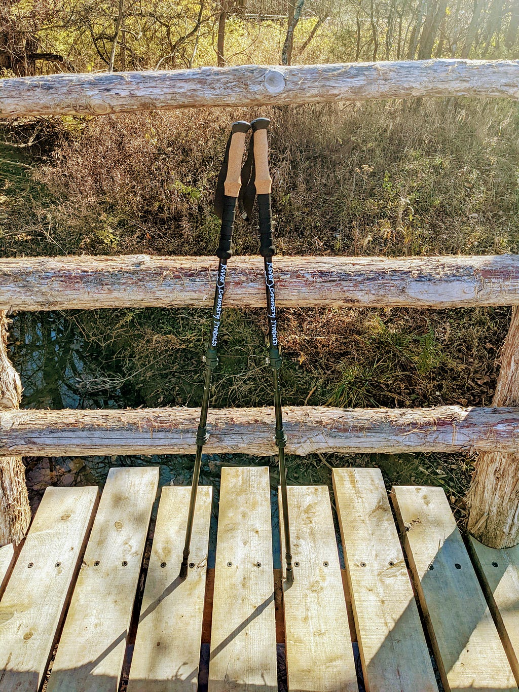 A pair of trekking poles leaning against a wooden bridge.