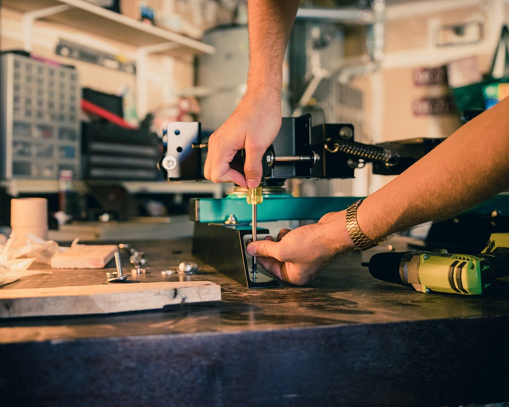 a person holding a screwdriver on a work bench