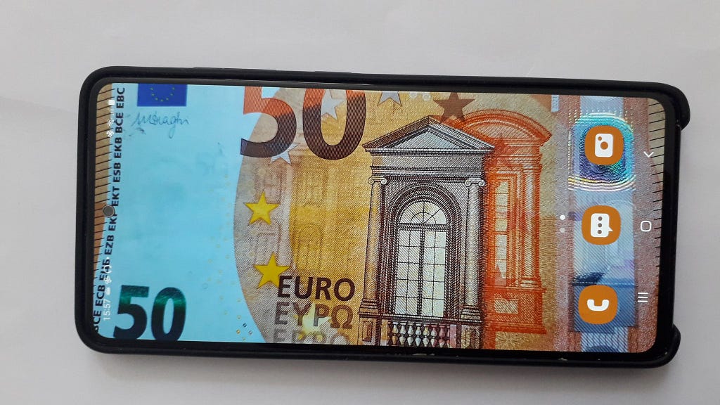 A smartphone that has a 50 euro note in the background on full screen.