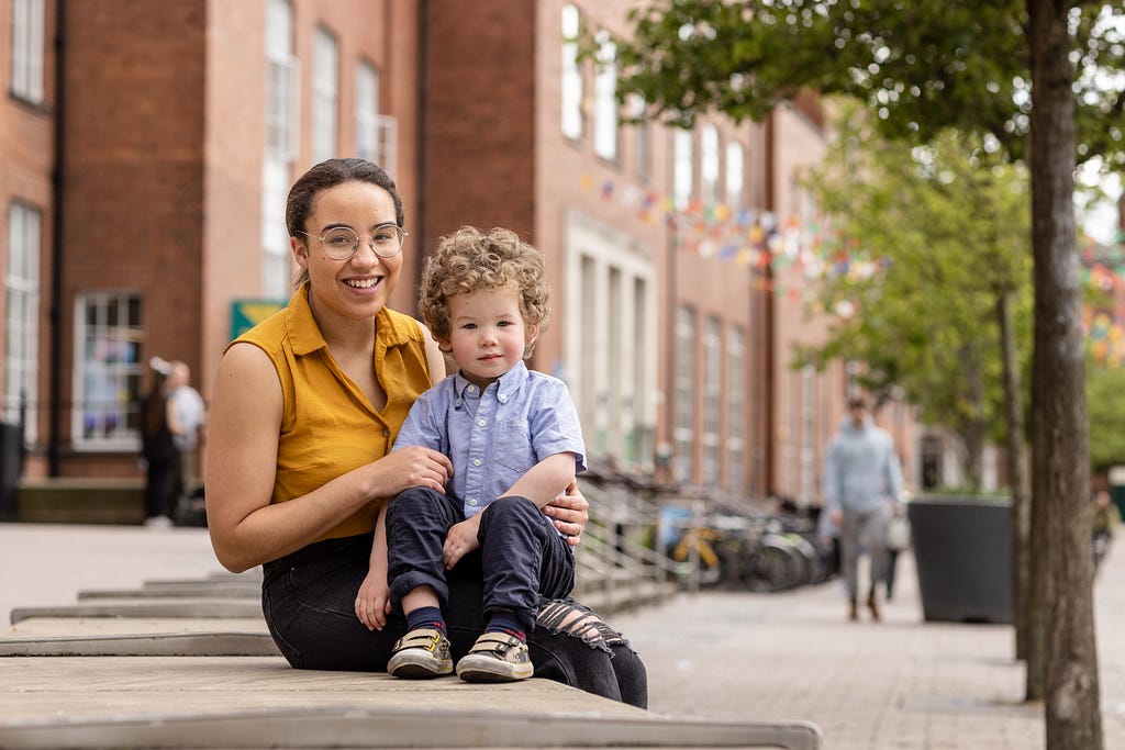A mature student at the University of Leeds, photographed with their child outside the Leeds University Union building.